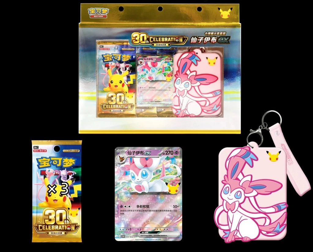 Pokémon 30th Anniversary Celebration set featuring a large blister pack with trading cards and a pink sylveon keychain, plus two smaller individual packs and a single card displayed on a black background.